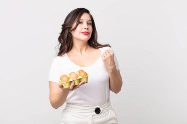 Güzel bir kadın küstah, başarılı, pozitif ve gururlu görünüyor ve elinde bir yumurta kutusu tutuyor.