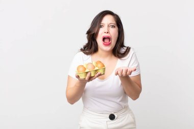 Güzel bir kadın umutsuz, sinirli ve stresli görünüyor ve elinde bir yumurta kutusu tutuyor.