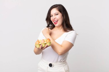 Güzel bir kadın kendini mutlu hisseder ve bir meydan okumayla yüzleşir ya da kutlama yapar ve bir yumurta kutusu tutar.