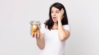 Güzel bir kadın mutlu, heyecanlı ve şaşırmış hissediyor ve elinde cam bir kurabiye şişesi tutuyor.