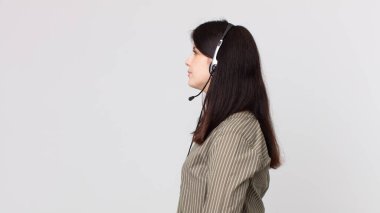 Profil görünümlü güzel bir kadın hayal kuruyor, hayal ediyor ya da hayal kuruyor. Kulaklıklı bir yardımcı ajan.