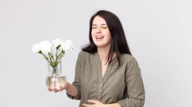 Güzel bir kadın komik bir şakaya yüksek sesle gülüyor ve elinde dekoratif bir çiçek tutuyor. Kulaklıklı bir yardımcı ajan.