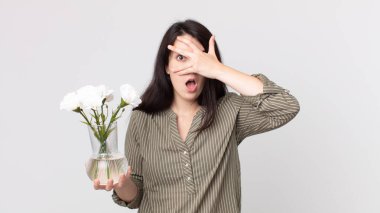 Güzel bir kadın şok olmuş, korkmuş ya da korkmuş görünüyor. Yüzü elle örtülmüş ve elinde dekoratif bir çiçek tutuyor. Kulaklıklı bir yardımcı ajan.