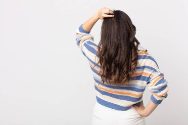 Güzel bir kadın bilgisiz ve kafası karışık, bir çözüm düşünüyor, eli kalçasında, diğeri kafasında, dikiz aynasından.