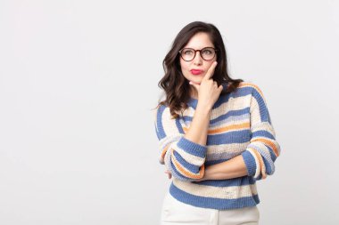 Güzel bir kadın ciddi, düşünceli ve güvensiz görünüyor, bir kolu çapraz ve elleri çenesinde, seçenekleri değerlendiriyor.