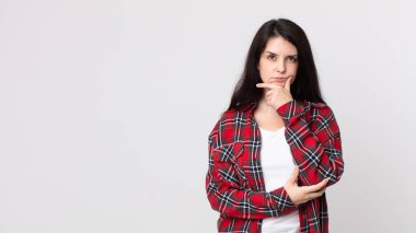 Güzel bir kadın ciddi, düşünceli ve güvensiz görünüyor, bir kolu çapraz ve elleri çenesinde, seçenekleri değerlendiriyor.