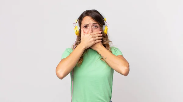 Dość Cienka Kobieta Zakrywająca Usta Dłońmi Zaszokowaną Muzyką Słuchania Słuchawkami — Zdjęcie stockowe