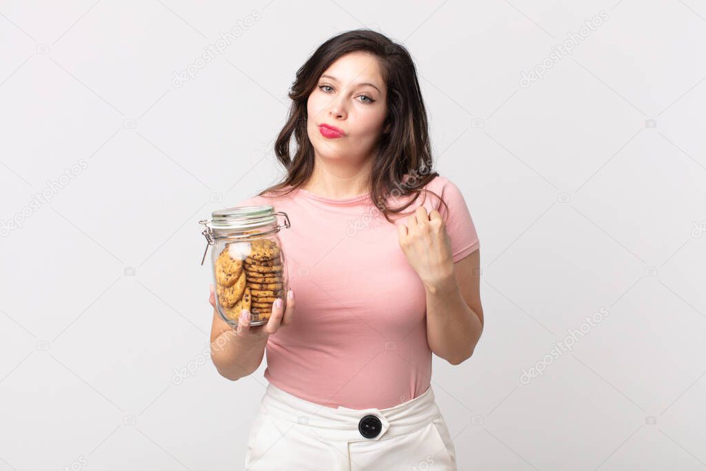 pretty woman looking arrogant, successful, positive and proud and holding a cookies glass bottle