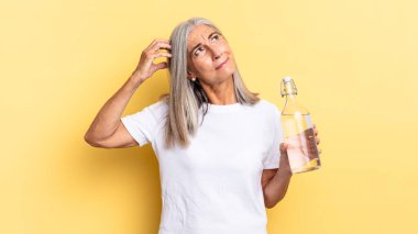 Gülümseyerek ve hayal kurarak ya da şüphe duyarak, yan tarafa bakarak ve su şişesini tutarak