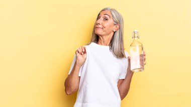 Kibirli, başarılı, pozitif ve gururlu görünüyor, kendini gösteriyor ve su şişesini tutuyor.