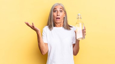 Ağzı açık ve şaşkın, şok olmuş ve hayretler içinde inanılmaz bir sürprizle ve elinde bir su şişesiyle