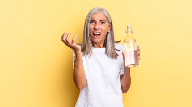 Çaresiz ve hayal kırıklığına uğramış görünüyor, stresli, mutsuz ve sinirli, bağırıyor, çığlık atıyor ve su şişesini tutuyor.