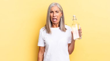 İğrençsin, sinirlisin, dilini dışarı çıkarıyorsun, iğrenç ve iğrenç bir şeyden hoşlanmıyorsun ve elinde bir su şişesi tutuyorsun.