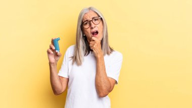 Ağzı ve gözleri sonuna kadar açık ve elleri çenesinde, hoş olmayan bir şokta, ne ya da vay canına diyor. astım konsepti