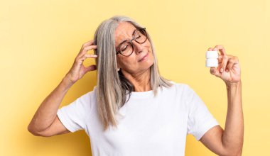 Mutlu bir şekilde gülümseyen ve hayal kuran ya da şüpheyle bakan, yan tarafa bakan ve bir hap şişesi tutan