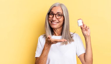 Neşeli bir şekilde gülümseyen, mutlu hisseden ve fotokopi alanında avuç içi haplarla dolu bir konsept gösteren