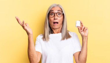 Ağzı açık ve şaşkın, şok olmuş ve hayretler içinde inanılmaz bir sürprizle ve elinde bir ilaç şişesiyle