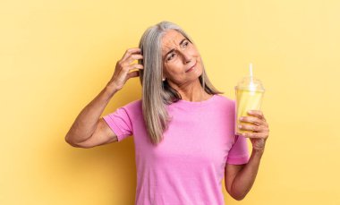 Mutlu bir şekilde gülümseyen ve hayal kuran ya da şüpheye düşen, yana bakan ve bir milkshake tutan