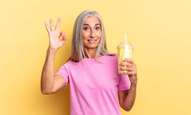 Mutlu, rahat ve tatmin olmuş hissediyorum. Onayını iyi bir jestle gösteriyorum. Gülümsüyorum ve elimde milkshake tutuyorum.