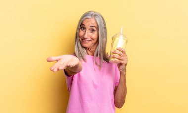 Mutlu bir şekilde gülümseyen, kendine güvenen, pozitif bakışlı, bir nesne ya da konsept sunan ve bir milkshake tutan