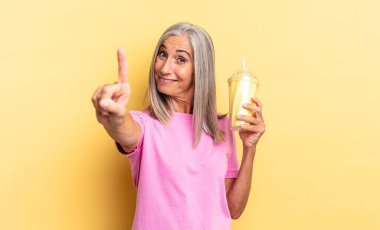 Gülümsüyor ve arkadaş canlısı görünüyor, bir numara ya da ilk eli önde, geri sayıyor ve milkshake tutuyor.