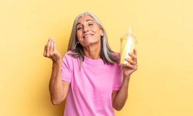 Kapiş ya da para hareketi yaparak, borçlarını ödemeni söyleyerek! Ve bir milkshake tutuyor.