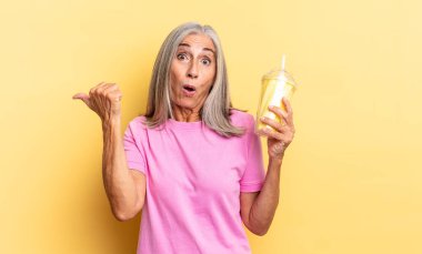 İnançsızlıktan şaşkına dönmüş, yan taraftaki nesneyi işaret ediyor ve 