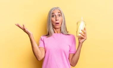 Ağzı açık ve şaşkın, şok olmuş ve hayretler içinde inanılmaz bir sürprizle ve elinde bir milkshake tutarak