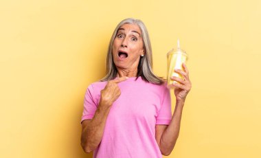 Şok olmuş ve şaşırmış bir halde, ağzı açık, kendini gösteren ve elinde milkshake tutan.