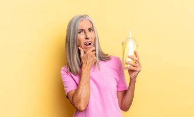 Ağzı ve gözleri sonuna kadar açık ve elleri çenesinde, kötü bir şokta, ne ya da wow diyor ve bir milkshake tutuyor.