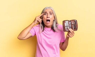 Mutlu, şaşkın ve şaşırmış görünüyor, gülümsüyor ve inanılmaz ve inanılmaz iyi haberleri fark ediyor ve elinde bir çivi çantası tutuyor.