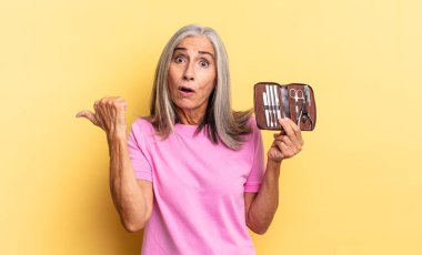 İnanamamaktan şaşkına dönmüş, yan taraftaki objeyi işaret ediyor ve 