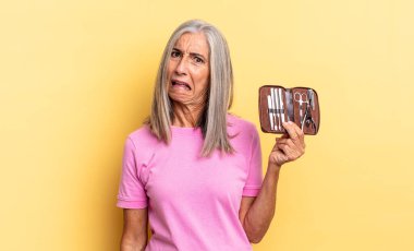 feeling puzzled and confused, with a dumb, stunned expression looking at something unexpected holding a nails tools case