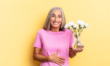 Komik bir şakaya yüksek sesle gülmek, mutlu ve neşeli hissetmek, dekoratif çiçekleri tutarak eğlenmek.