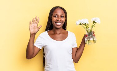 Gülümsüyor ve dost canlısı görünüyor. 5 ya da 5 numarayı gösteriyor. Elleri önde, geriye doğru sayıyor. Dekoratif çiçek konsepti