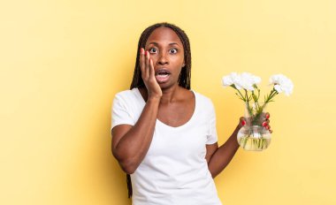 Şok olmuş ve korkmuş hissediyorum, ağzı açık ve elleri yanaklarında korkmuş görünüyor. Dekoratif çiçek konsepti