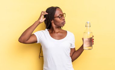 Mutlu bir şekilde gülümsüyor ve hayal kuruyor ya da şüphe ediyor, yana bakıyor. su şişesi kavramı