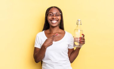 Neşeli bir şekilde gülümseyen, mutlu hisseden, kenarı ve yukarıyı gösteren, fotokopi uzayındaki nesneleri gösteren. su şişesi kavramı