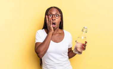 Şok olmuş ve korkmuş hissediyorum, ağzı açık ve elleri yanaklarında korkmuş görünüyor. su şişesi kavramı