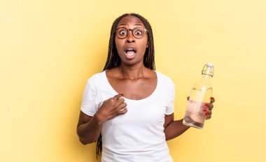 Şok olmuş ve ağzı açık, kendini işaret ederek şaşırmış görünüyordu. su şişesi kavramı