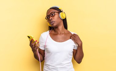 Stresli, endişeli, yorgun ve hayal kırıklığına uğramış, tişörtünü çekmiş, sıkıntılı görünüyor ve müzik dinliyor.