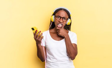 Ağzı ve gözleri sonuna kadar açık ve elleri çenesinde, hoş olmayan bir şok içinde, ne ya da vay be diyerek ve müzik dinleyerek.