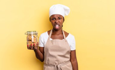 Siyah afro şef kadın tiksinmiş ve rahatsız olmuş hissediyor, dilini dışarı çıkarıyor, çirkin ve iğrenç bir şeyden hoşlanmıyor. kurabiye konsepti