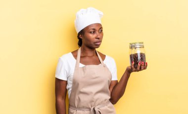 Siyah afro şef kadın üzgün, üzgün ya da kızgın hissediyor ve olumsuz bir tavır takınıyor, anlaşmazlık içinde kaşlarını çatıyor. kahve çekirdeği konsepti