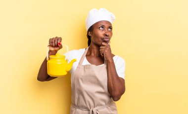 Siyah afro şef kadın düşünüyor, kuşkulu ve şaşkın hissediyor, farklı seçeneklerle, hangi kararı vereceğini merak ediyor. çaydanlık konsepti