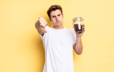 Kızgın, sinirli, hayal kırıklığına uğramış ya da hoşnutsuz, ciddi bir bakışla başparmaklarını aşağı gösteren. kahve çekirdeği konsepti