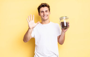 Gülümsüyor ve dost canlısı görünüyor. 5 ya da 5 numarayı gösteriyor. Elleri önde, geriye doğru sayıyor. kahve çekirdeği konsepti