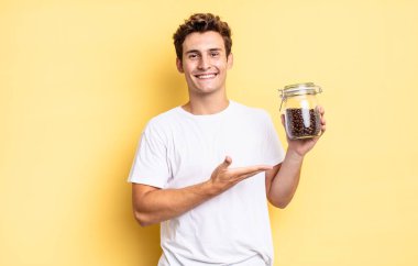 Neşeli bir şekilde gülümseyen, mutlu hisseden ve fotokopi uzayında avucunun içinde bir konsept gösteren. kahve çekirdeği konsepti