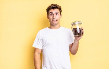 Şaşırmış ve kafası karışmış görünüyor, sinirsel bir hareketle dudağını ısırıyor, sorunun cevabını bilmiyor. kahve çekirdeği konsepti