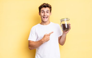 Heyecanlı ve şaşırmış görünüyor. Yana doğru ve yukarı doğru uzayı gösteriyor. kahve çekirdeği konsepti